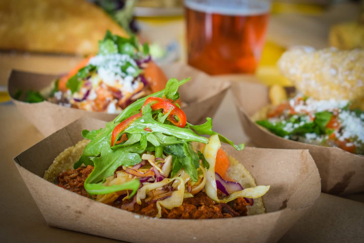 Three different tacos sit in individual paper trays.