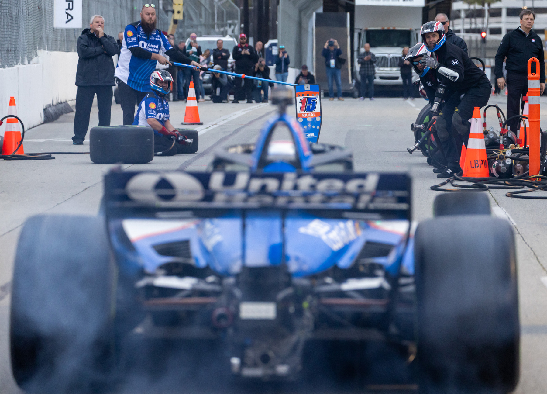 The Indycar pit crew gets ready as Graham Rahal comes down the track during the Indy Series pit stop competitions at the Pike Outlets