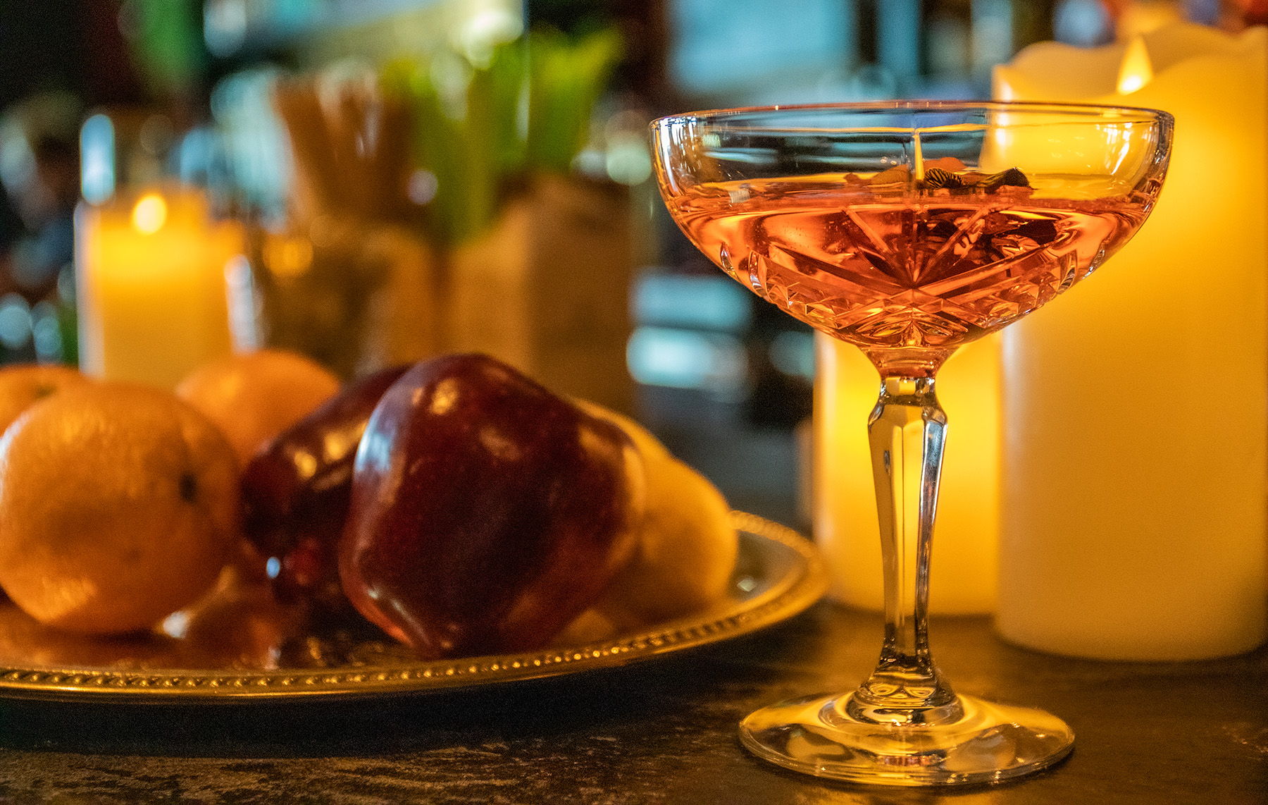 A cocktail drink sits next to a tray of fruit.