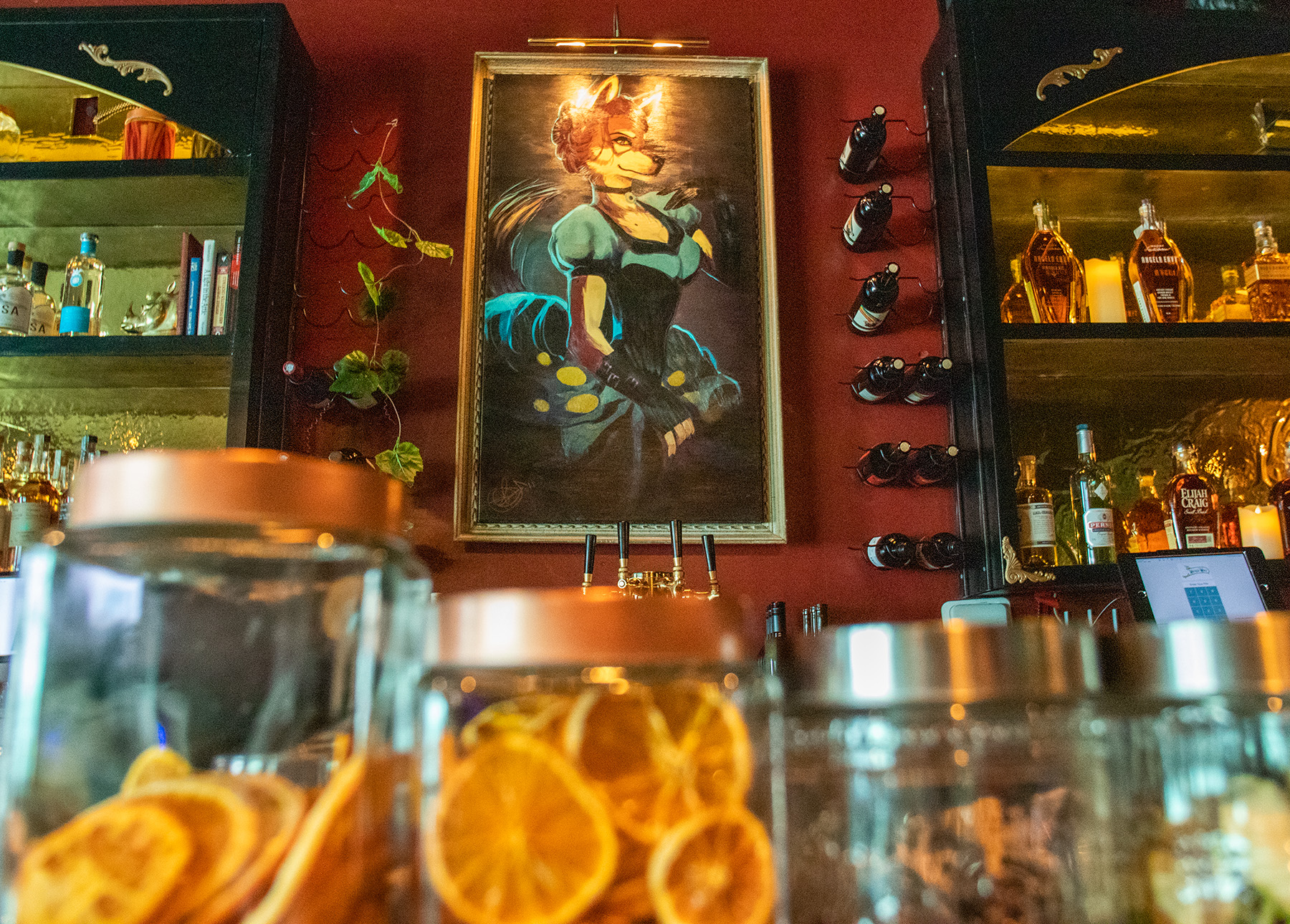 A painting of a female wolf hangs above a bar.