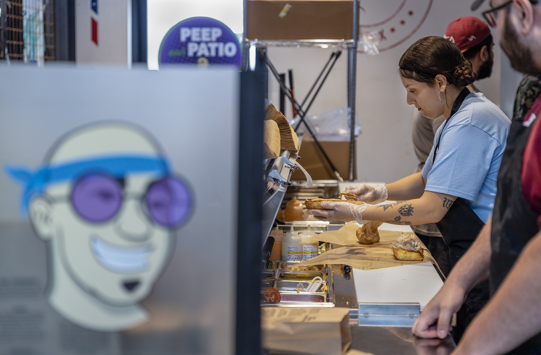 A woman spreads sauce on bread as she makes a sandwich