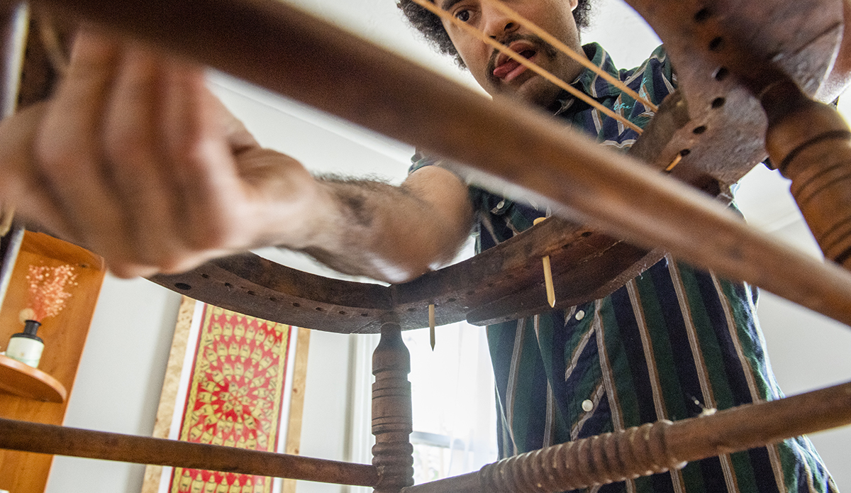 Weaves a seat of a chair while working in his work studiofurniture repair.