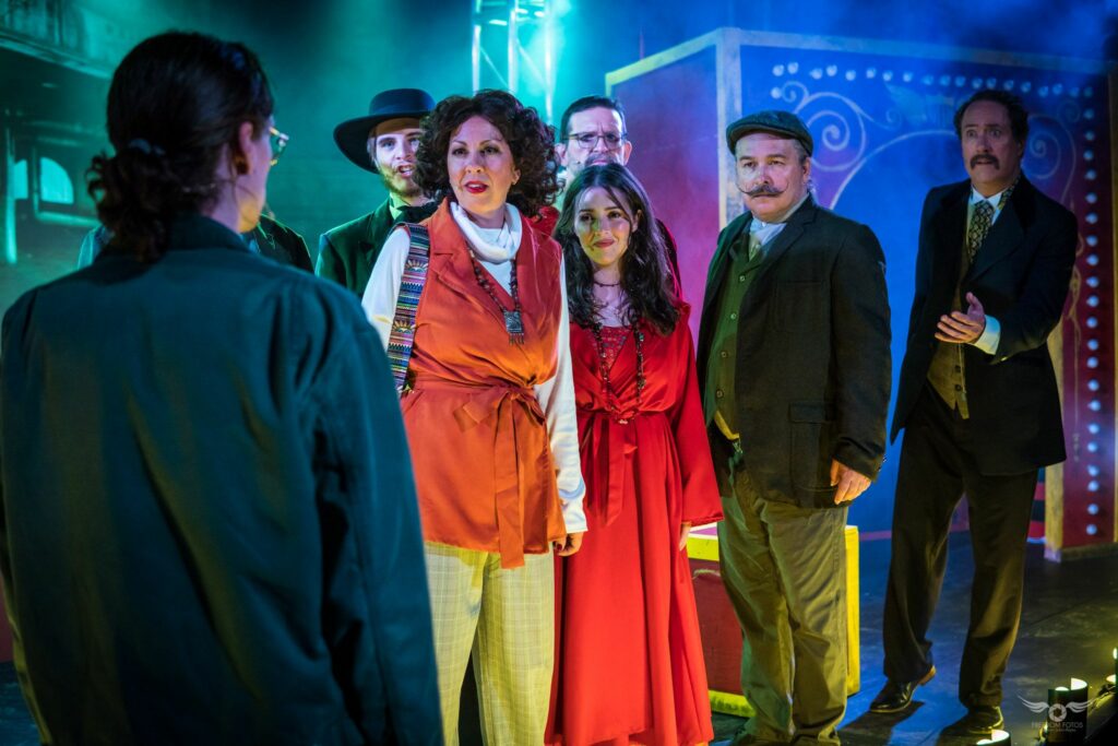 Actors dressed in 1920s European attire sing on a multi-colored stage.