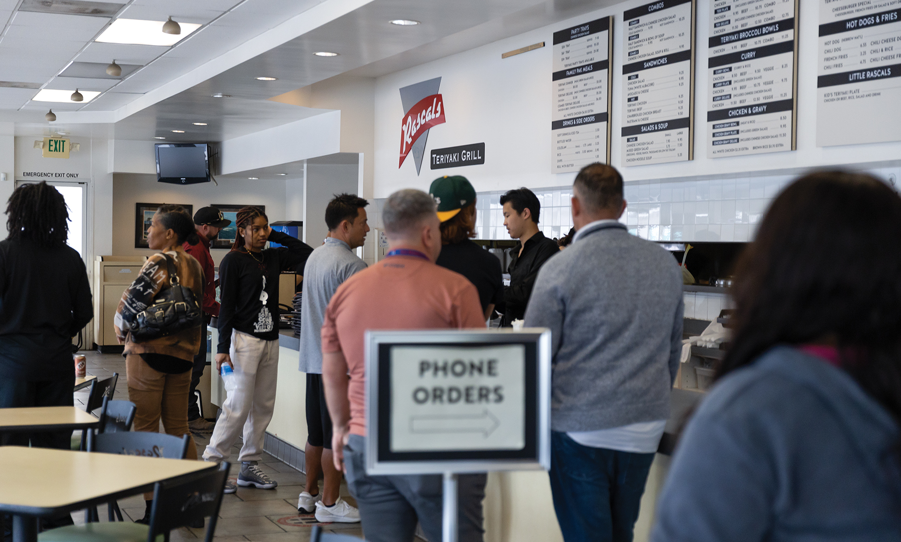 People wait in line to order food inside a fast-casual restaurant.