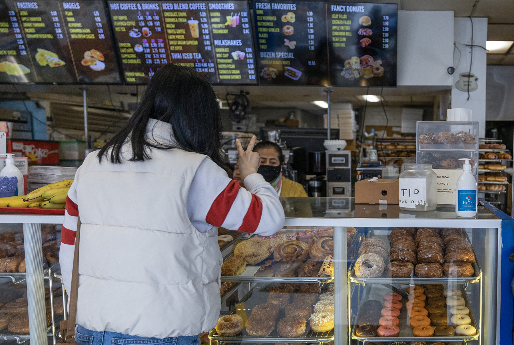 A person holds up two fingers while ordering doughnuts.