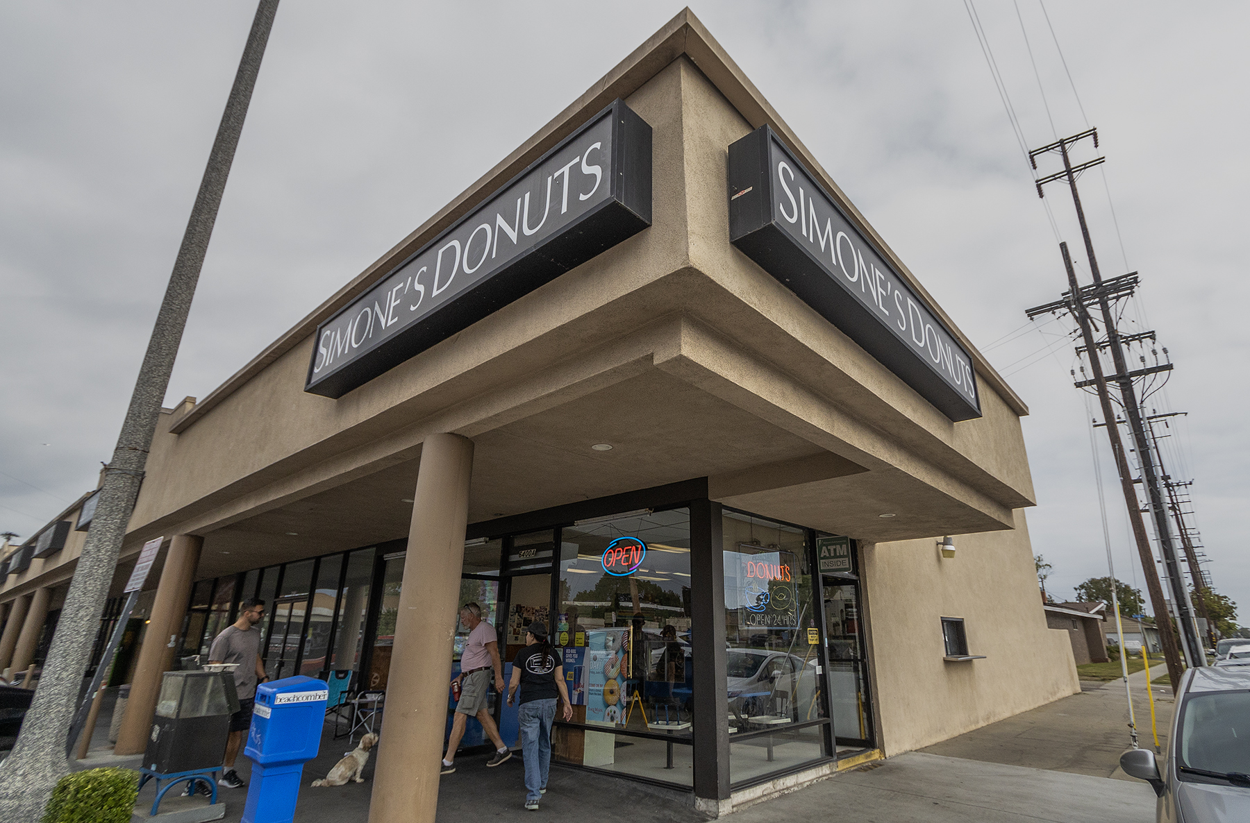 People walk into and out of a corner doughnut shop.