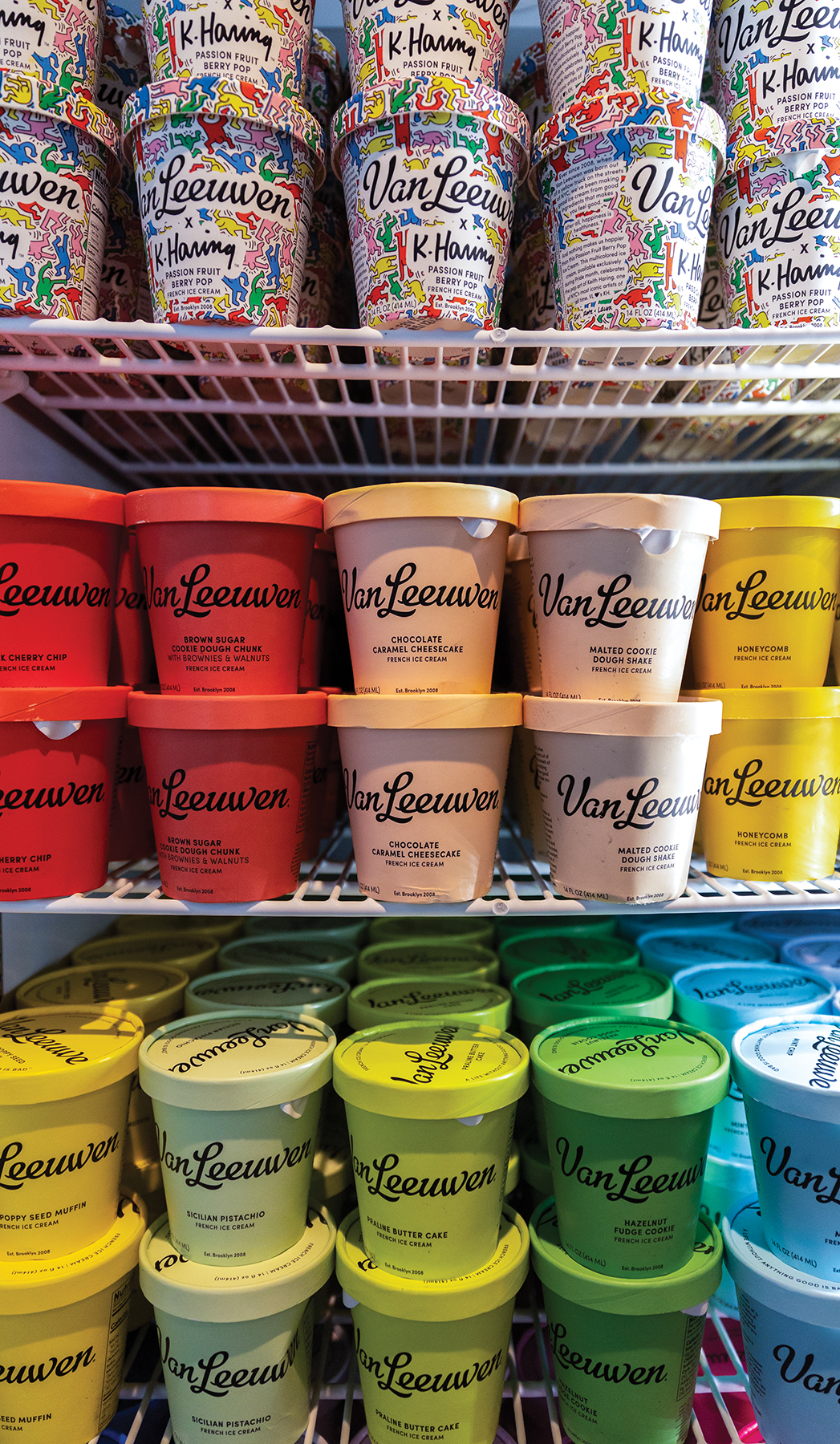 Pints of ice cream stacked in a refrigerator.