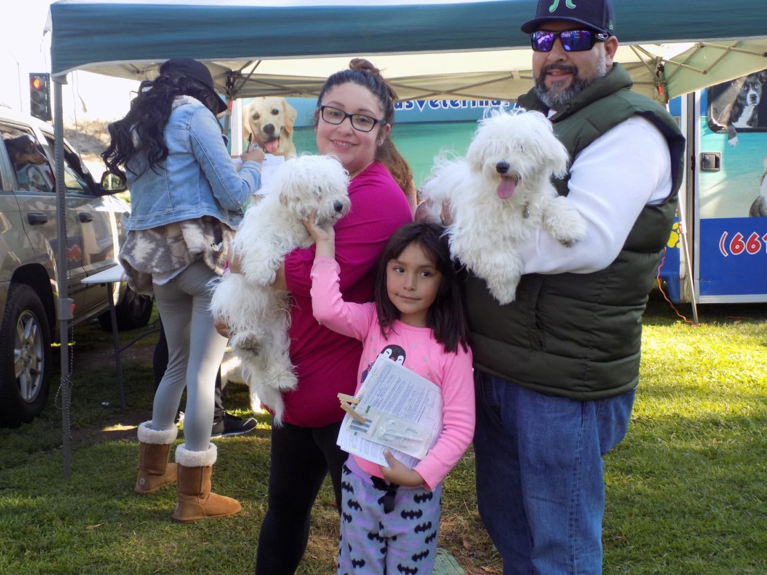 FAmily --mother, father, and little girl carry two fluffy dogs