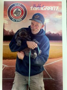 A baseball card features a man holding a dog.