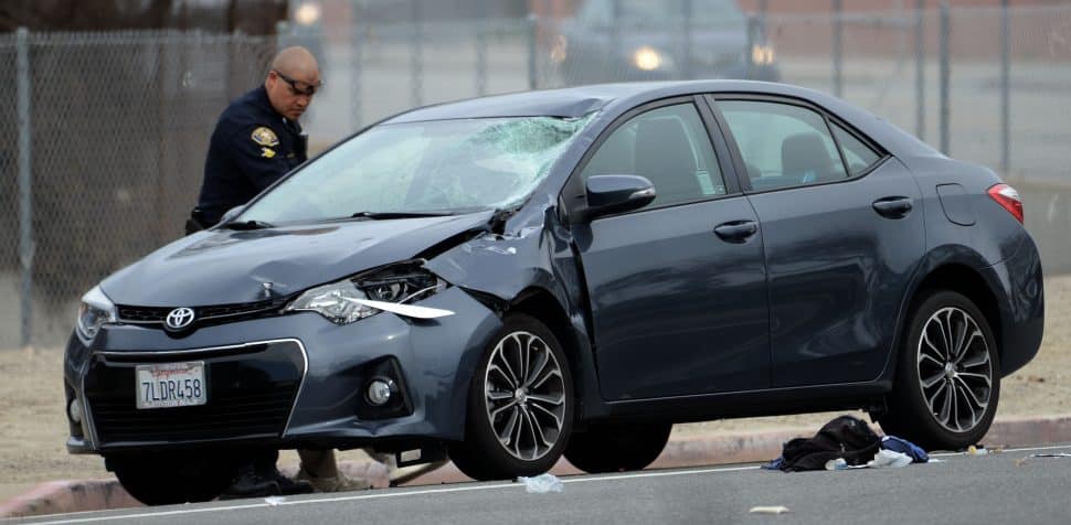 A Long Beach Police inspects a damaged car involved in a fatal accident, involving a bicyclist, at the corner of Los Coyotes Diagonal and Palos Verdes Avenue, Wednesday January 30th, 2019. Photo by Stephen Carr / For the Long Beach Post