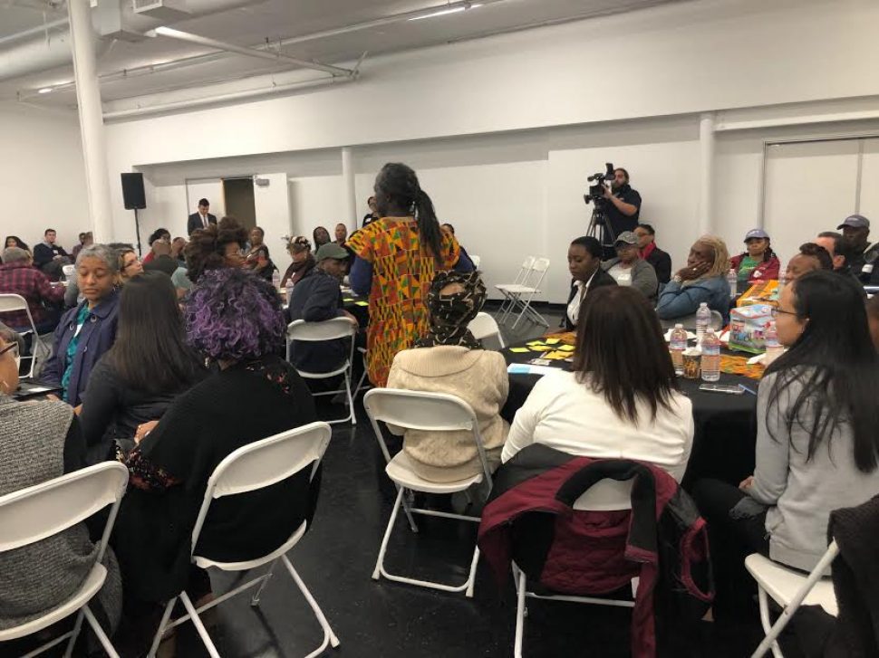 A man dressed in African print attire speaks to a big crowd.