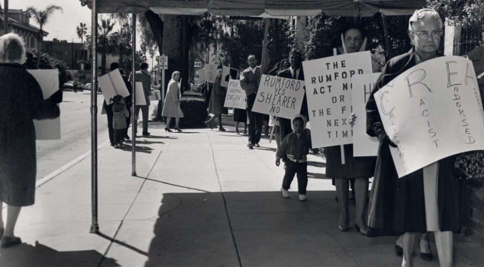 A black-and-white picture shows people marching with protest signs against Prop. 14.