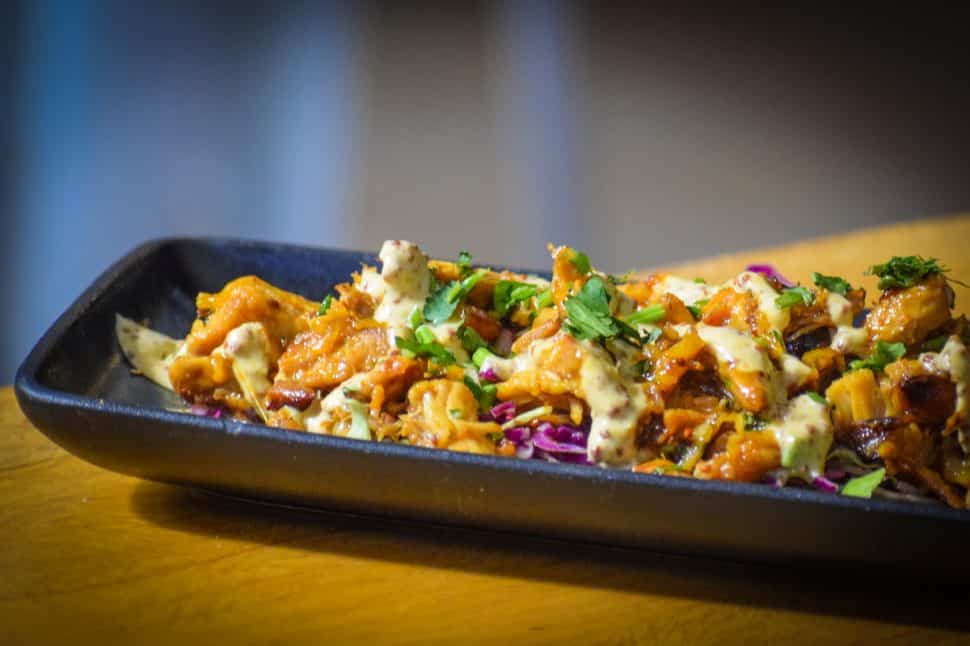 An array of chicken bits sit on a black plate with purple cabbage.